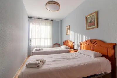 a hotel room with two beds and a window at Global Vacacional, Piso práctico, con terraza y piscina en la playa de Canet in Canet de Berenguer
