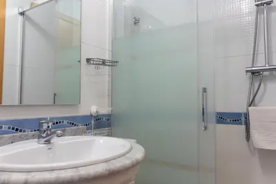 a white bathroom with a sink and a shower at Global Vacacional, Piso práctico, con terraza y piscina en la playa de Canet in Canet de Berenguer