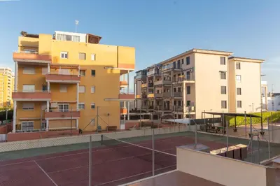 a tennis court in front of some buildings at Global Vacacional, Piso práctico, con terraza y piscina en la playa de Canet in Canet de Berenguer