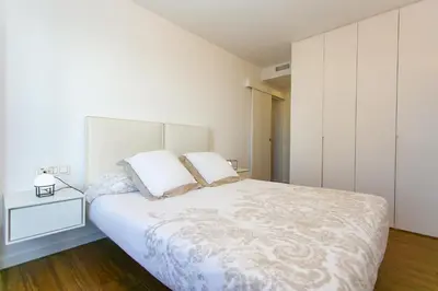 a white bedroom with a large bed and a nightstand at Cullera Beach Apartment Espacio in Cullera