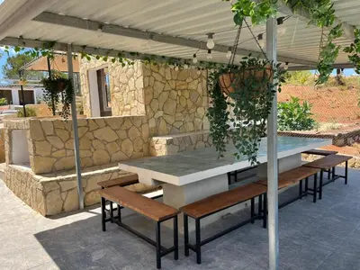 a patio with a table and benches and a stone wall at Casa de campo Ismael in Siete Aguas