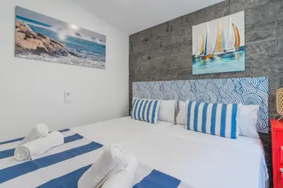 a bedroom with a white bed with blue and white pillows at Alojamiento Náutico Junto a la Playa Malvarrosa in Valencia