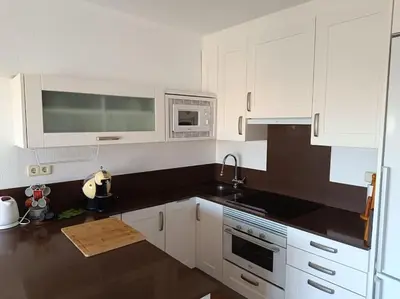 a kitchen with white cabinets and a black counter top at Beach Nice Flat in Playa Pobla de Farnals