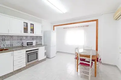 a kitchen with white cabinets and a table with chairs at Global Vacacional, Apartamento céntrico en Puerto de Sagunto para 5 personas in Puerto de Sagunto