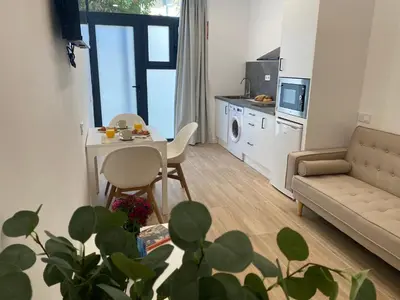 a living room with a couch and a table and a kitchen at Travel Habitat Cabanyal Lofts in Valencia