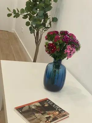 a blue vase with flowers on a table with a magazine at Travel Habitat Cabanyal Lofts in Valencia