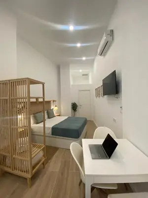 a bedroom with a bed and a desk with a laptop at Travel Habitat Cabanyal Lofts in Valencia