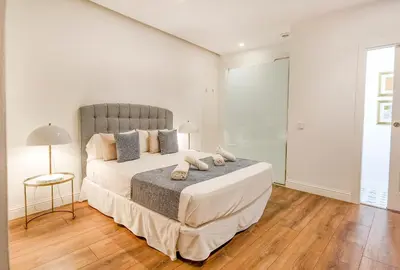 a white bedroom with a large bed and a table at Torres de Serranos Apartments - TTdSSa VLC in Valencia