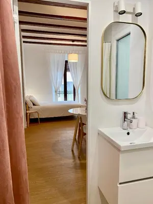 a bathroom with a sink and a mirror and a bedroom at RIZADA RUZAFA in Valencia