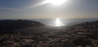 a beach with the sun shining on the water at EL RINCÓN VERDE in Puerto de Sagunto