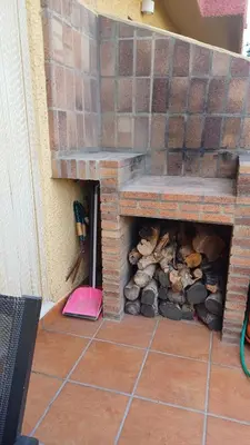a brick fireplace with a pile of fire wood at Adosado/casa con terraza y buhardilla. Playa El Perelló in El Perelló