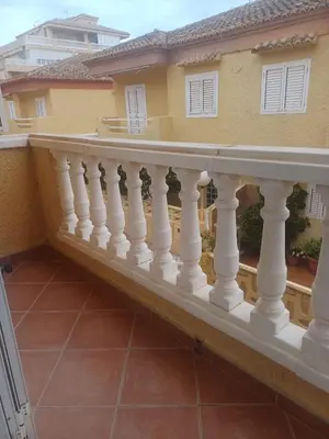 a balcony with white railings on a house at Adosado/casa con terraza y buhardilla. Playa El Perelló in El Perelló