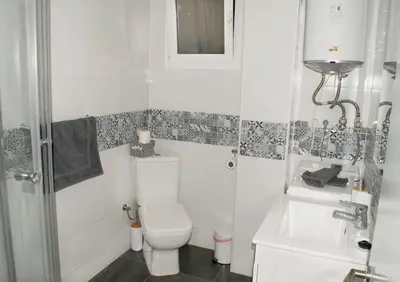 a white bathroom with a toilet and a sink at El Camino Del Mar in Valencia