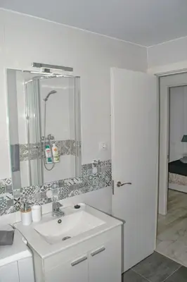 a white bathroom with a sink and a mirror at El Camino Del Mar in Valencia