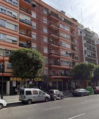 a street with cars parked in front of a tall building at El Camino Del Mar in Valencia