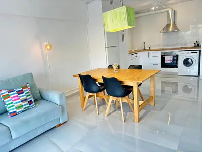 a kitchen with a wooden table and a blue couch at Apt. En la Playa, Wifi rápido y piscina. in Puebla de Farnals