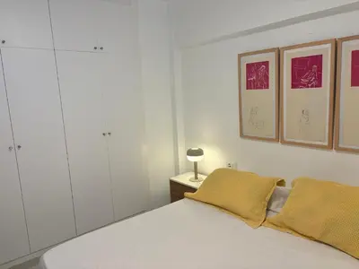 a bedroom with a white bed with two yellow pillows at Apt. En la Playa, Wifi rápido y piscina. in Puebla de Farnals