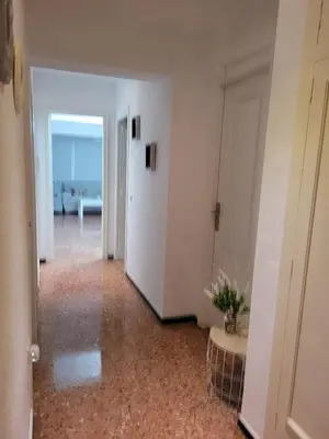 a hallway with a room with white walls and a table at Amplio apartamento in Puebla de Farnals