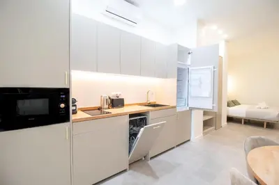 a kitchen with white cabinets and a table and a bed at Favara Flats by Concept in Valencia