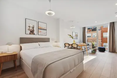 a bedroom with a large white bed and a table at Limehome Valencia Carrer del Pare Palau i Quer in Valencia
