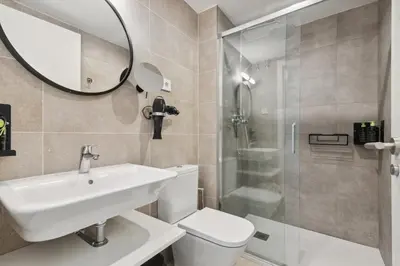a bathroom with a toilet and a sink and a shower at Limehome Valencia Carrer del Pare Palau i Quer in Valencia