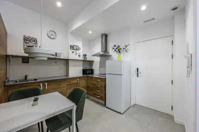 a white kitchen with a table and a refrigerator at Amazinn Valencia Cabanyal 2C in Valencia