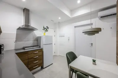 a kitchen with a white refrigerator and a table at Amazinn Valencia Cabanyal 2C in Valencia