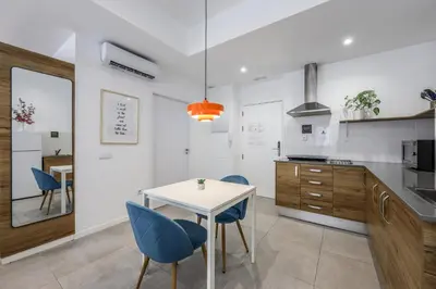 a kitchen with a white table and blue chairs at AmazINN Valencia Cabanyal 3B in Valencia