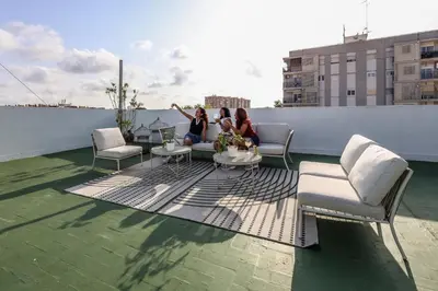 three women sitting on a rooftop patio on a building at Amazinn Valencia Cabañal 3A in Valencia