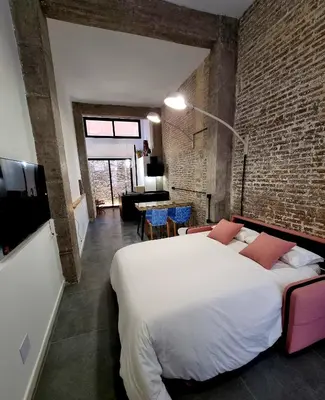 a bedroom with a white bed and a brick wall at cactus loft Ruzafa in Valencia
