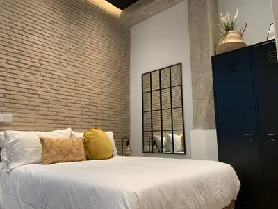 a bedroom with a white bed and a brick wall at La Reina Beach rooms in Valencia