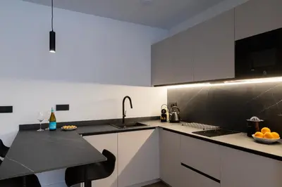 a kitchen with white cabinets and a black counter top at Demetrio By Alma Suites in Valencia
