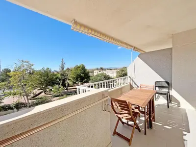a balcony with a wooden table and chairs on it at Global Vacacional, Apartamento de 3 dormitorios y terraza en la playa de Canet in Canet de Berenguer
