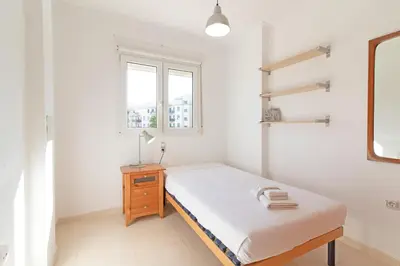 a white bedroom with a bed and a window at Global Vacacional, Apartamento de 3 dormitorios y terraza en la playa de Canet in Canet de Berenguer