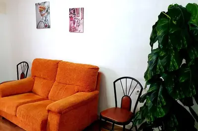 an orange couch in a living room with a plant at Casa rural para 8 huéspedes en plena naturaleza in Gestalgar