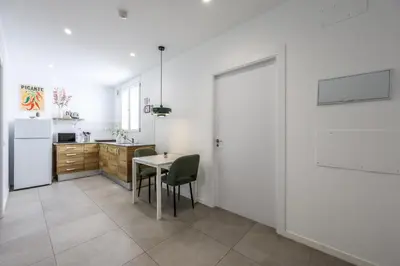a kitchen with a table and chairs and a refrigerator at AmazINN Valencia Cabanyal 3D in Valencia