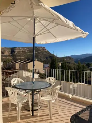a table and chairs with an umbrella on a balcony at Chulillagreenhouse in Chulilla