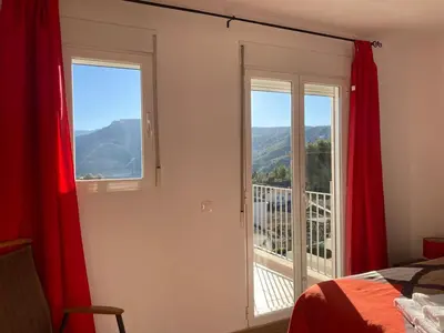 a bedroom with red curtains and a view of a balcony at Chulillagreenhouse in Chulilla