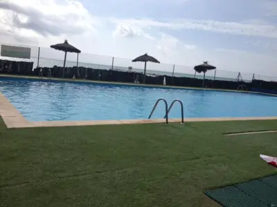 a large swimming pool with umbrellas on the grass at Modern Penthouse-duplex Facing The Sea in La Torre