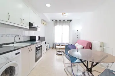 a white kitchen with a table and a sink at Global Vacacional, Práctico apartamento muy cerca del mar en Puerto Sagunto in Puerto de Sagunto