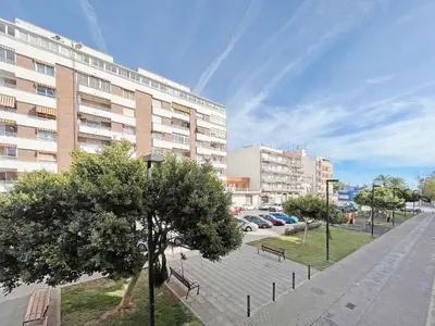 a park with benches and a tree in front of a building at Global Vacacional, Práctico apartamento muy cerca del mar en Puerto Sagunto in Puerto de Sagunto