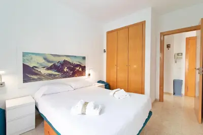 a bedroom with two beds and a painting on the wall at Global Vacacional, Práctico apartamento muy cerca del mar en Puerto Sagunto in Puerto de Sagunto
