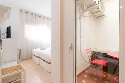a small room with a bed and a table and a desk at Global Vacacional, Práctico apartamento en Puerto de Sagunto cerca de la playa in Puerto de Sagunto