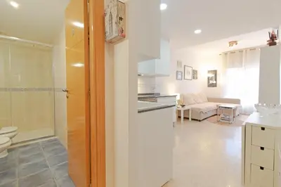 a white bathroom with a toilet and a kitchen at Global Vacacional, Práctico apartamento en Puerto de Sagunto cerca de la playa in Puerto de Sagunto