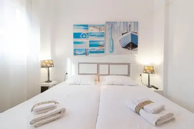a white bedroom with two towels on a bed at Global Vacacional, Práctico apartamento en Puerto de Sagunto cerca de la playa in Puerto de Sagunto