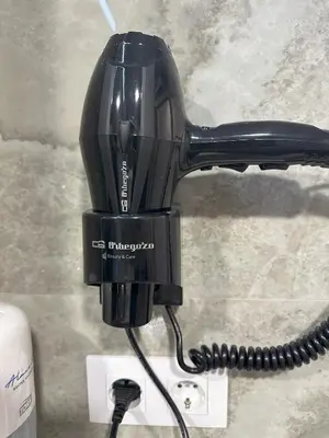 a black hair dryer is plugged into a cord at Almar 52 Suites in Valencia