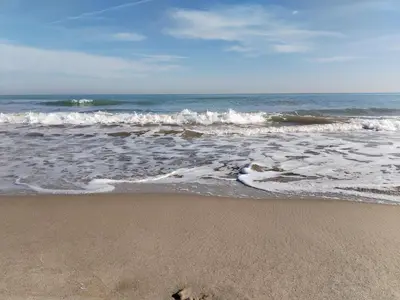 a sandy beach with waves in the ocean at COSTA AZUL in Puerto de Sagunto