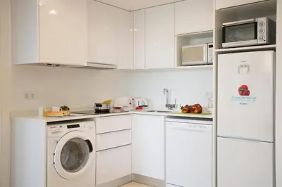 a kitchen with white cabinets and a washer and dryer at SingularStays Alameda II in Valencia