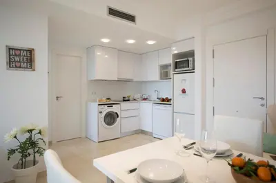 a white kitchen with a table and a kitchen with a washing machine at SingularStays Alameda II in Valencia
