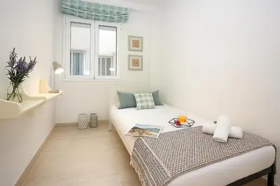 a small white room with a bed and a window at SingularStays Calderon in Valencia